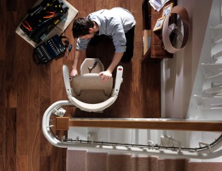 A Stannah ACME technician works on a stairlift in a customer's home